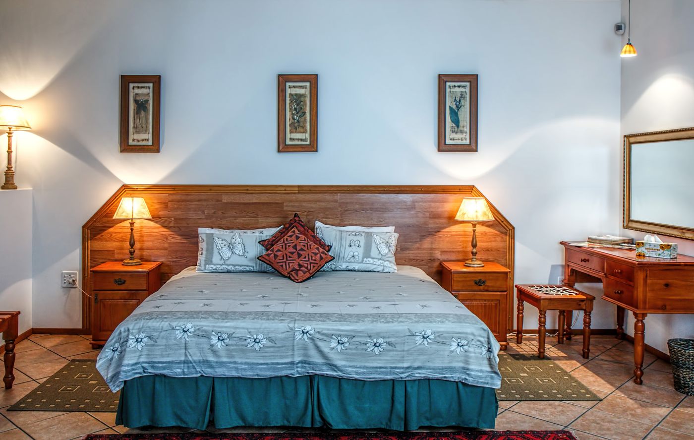 Hotel bedroom with timber furniture, bedside lighting and a large bed
